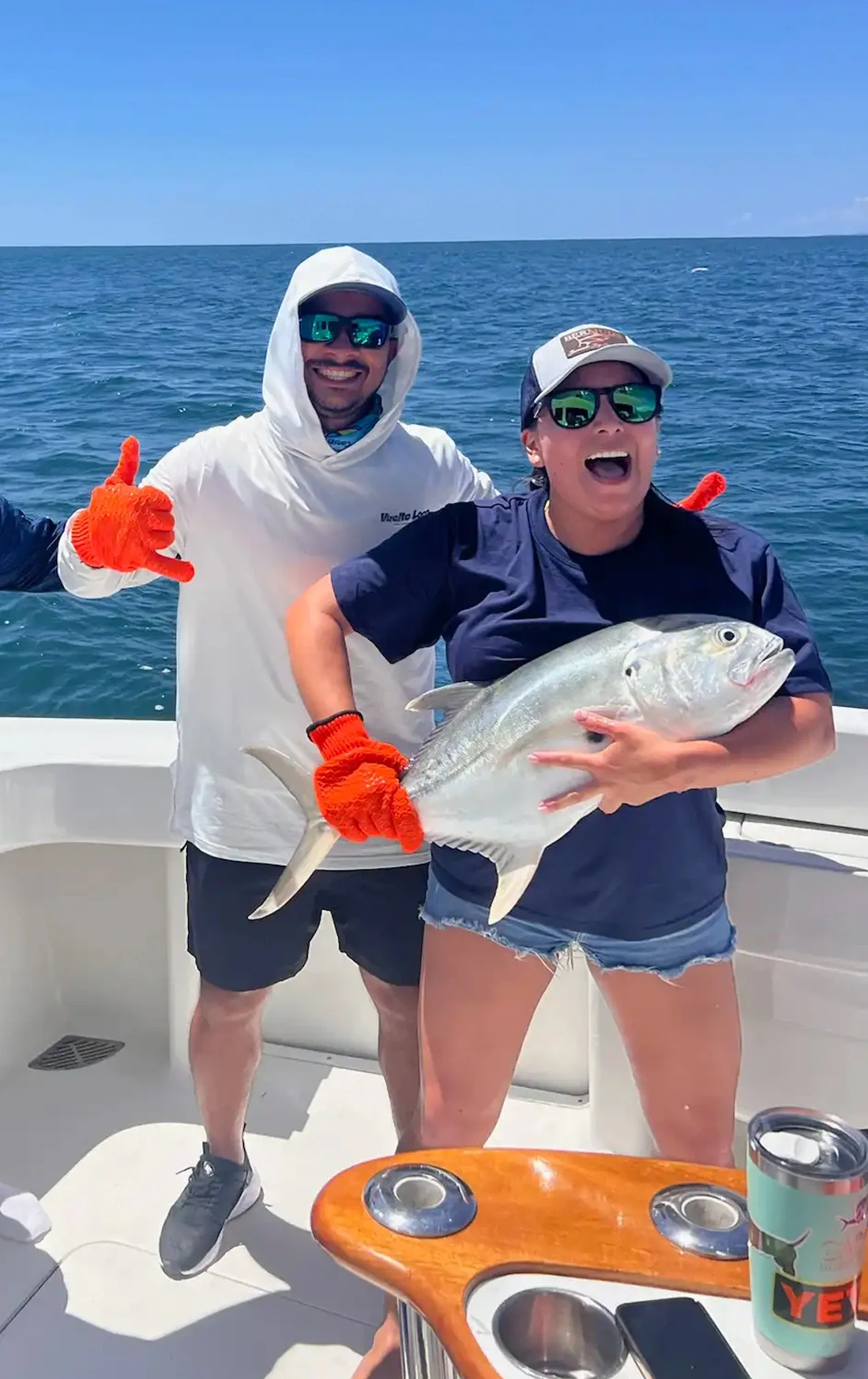 Nella and a guest holding a freshly caught fish on the deck of the Vuelto Loco